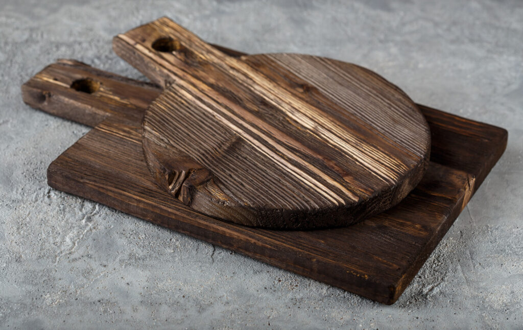 on a grey surface is a couple of wooden cutting boards, one round an done rectangular, both with handles