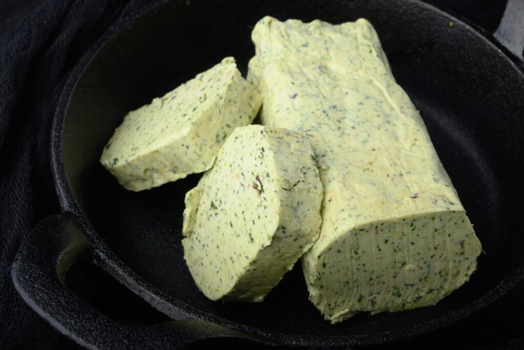 herbed butter on a black dish, in representation of the article "How to Store Fresh Herbs: 3 Ways to Preserve These Flavor Boosters" by My Kitchendom