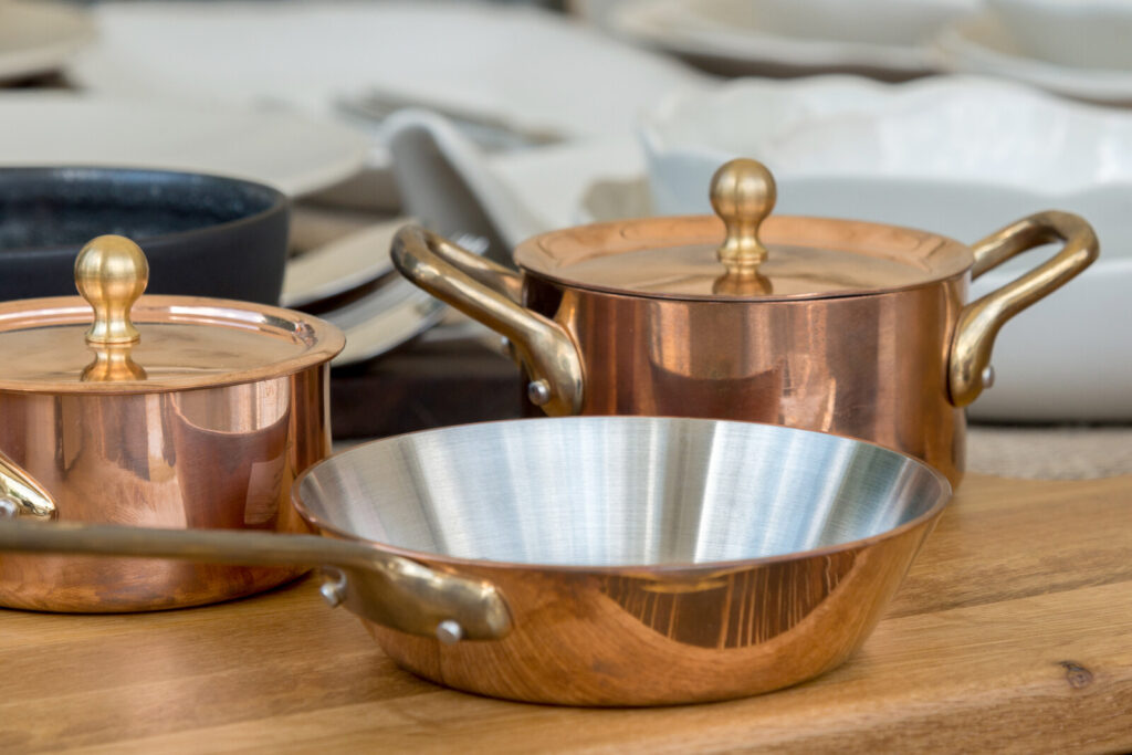 a set of two pots in two sizes and a pan on top of a wooden surface