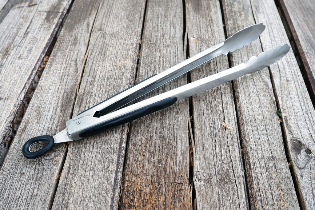 a metal tong on a rustic-looking wooden surface