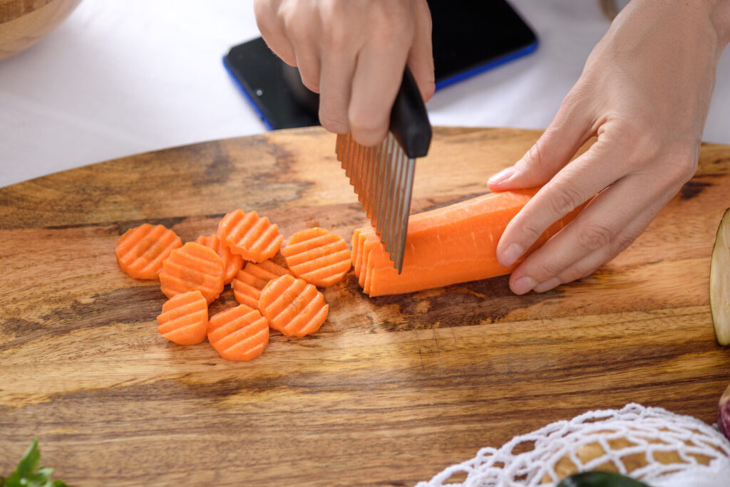 crinkle blade being used to slice carrots, it's one of the kitchen tools in the list