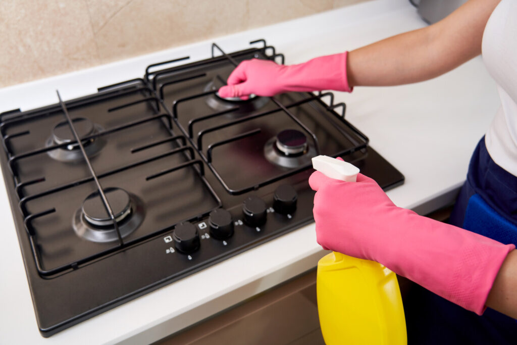 partial image of a woman cleaning her stove top