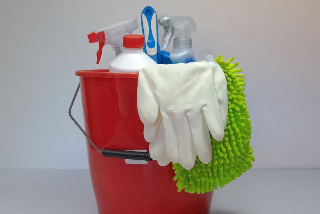 a red plastic pail with cleaning tools and supplies representing the article "New Year, New Kitchen: The Best Way To Organize Kitchen" by My Kitchendom