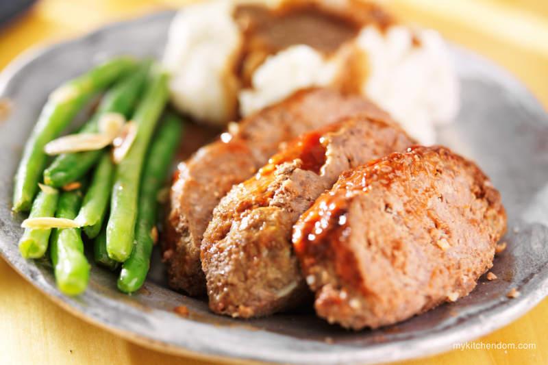 a serving of comfort food - sliced meatloaf with a side of asparagus and mashed potatoes